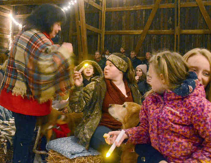 Cheri Williams of Canfield passes a candle light to others in her row in the barn as the congregation prepares to end the service singing "Silent Night."